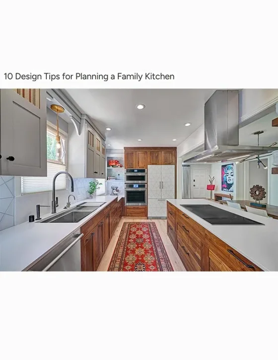 Modern kitchen with gray upper cabinets, wooden lower cabinets, white countertops, stainless steel appliances, a red patterned rug, and a colorful wall art in the dining area.