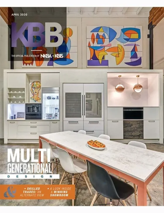 Modern kitchen with white cabinetry and colorful abstract artwork on the wall, a kitchen island with chairs, and a magazine cover with headlines about multi-generational design.