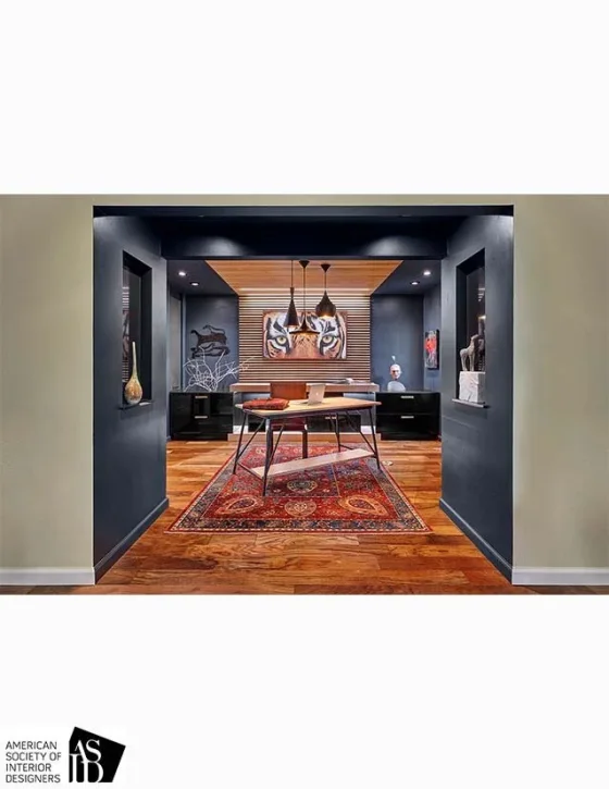 Interior view of a room framed by dark walls, featuring a wooden dining table, a colorful Persian rug, and modern art on the back wall.